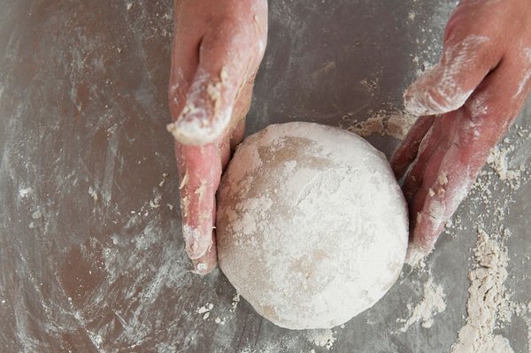 Sauerteig wird zu einer Kugel geformt auf einer grauen Arbeitsplatte